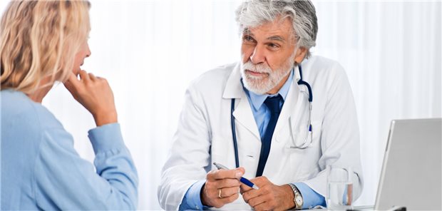 Welche Unterstützung Krebspatienten von ihren Hausärzten erwarten Eine Frau sitzt einem älterem Arzt gegenüber.