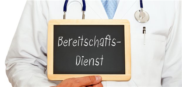 Arzt hält ein Schild mit der Aufschrift &quot;Bereitschaftsdienst&quot; hoch.