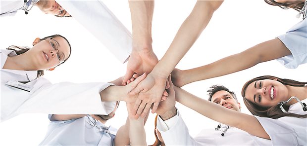 Cochrane-Review: Ärztliche Aufgaben lassen sich sicher auf Pflegefachkräfte übertragen Mehrere Menschen in weißer Kleidung stehen im Kreis und halten die Hände übereinander.