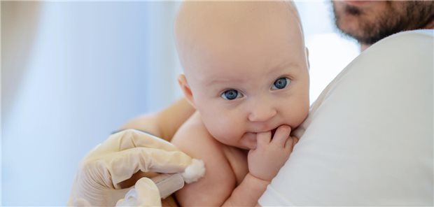 Ein Baby auf dem Arm eines Mannes erhält eine Impfung