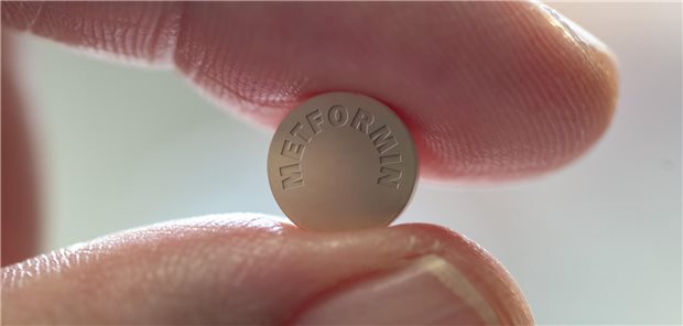 Unter Metformin regelmäßig Vitamin B12 kontrollieren Eine Person hält zwischen Daumen und Zeigefinger eine Metformin-Tablette.