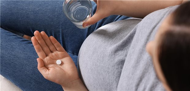 Antikonvulsiva während der Schwangerschaft bergen wohl ein Risiko für Neuroentwicklungsstörungen Eine schwangere Frau hält eine Tablette in der einen Hand und in der anderen Hand ein Glas Wasser.