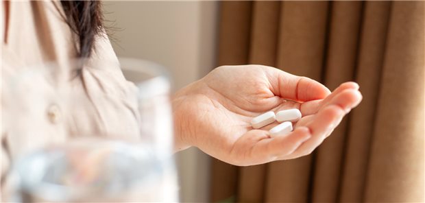 Nach Antidepressiva-Stopp: Fast die Hälfte mit deutlichen Symptomen Eine Frau mit drei Tabletten und einem Glas Wasser in der Hand.