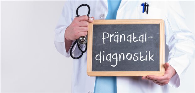 Bluttest auf Trisomien zu leichtfertig eingesetzt? Fachleute sind uneins Das Foto zeigt eine Tafel mit der Aufschrift "Pränatal-Diagnostik", die von einer Person mit Stethoskop in der Hand gehalten wird.