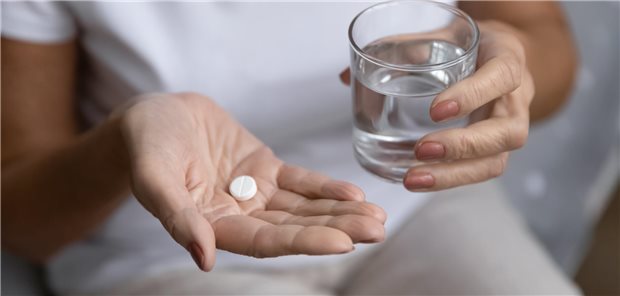 ASS schützt Senioren langfristig wohl nicht vor Krebs Person mit weißer Pille in der rechten Hand und Glas Wasser in der linken Hand