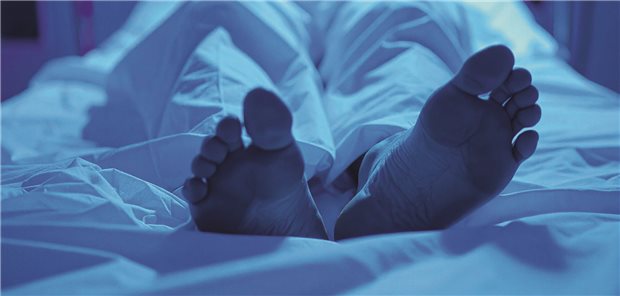 Zehn Praxis-Tipps für die Leichenschau Die Füße einer Leiche auf einem Bett, die Beine zugedeckt mit weißem Tuch.