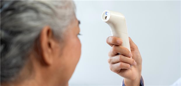 Hypothermie bei Sepsis – ein Warnsignal! Eine Krankenschwester misst die Temperatur einer älteren Frau mit einem berührungslosen Infrarot-Thermometer.