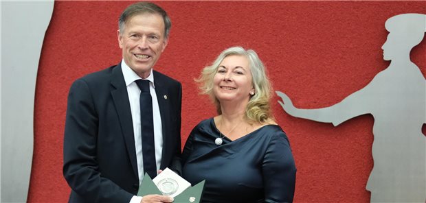 Antje Bergmann, Sachsens erste Professorin für Allgemeinmedizin, steht mit Matthias Rößler, Landtagspräsident, in einem Saal. Die Ärztin wurde mit der Sächsischen Verfassungsmedaille ausgezeichnet.
