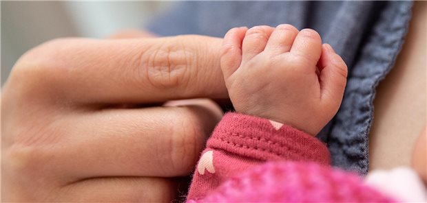 Hand eines Säuglings hält den Finger eines Erwachsenen fest