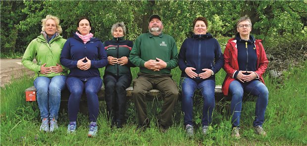 Menschen atmen auf einer Bank im Wald intensiv ein.