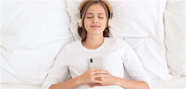 Musik, White Noise, ASMR – helfen Geräusche meinen Patienten beim Einschlafen? Schlafende Frau, die etwas über Kopfhörer hört