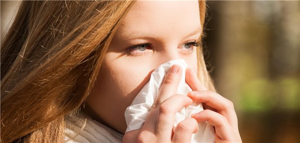 Höhepunkt der Grippewelle wohl überschritten Eine junge Frau putzt sich die Nase