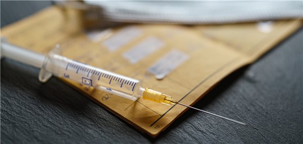 Impfen bei Immundefizienz: Worauf es ankommt Eine Impf-Spritze liegt auf einem Impfpass.