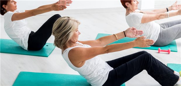 Brustkrebs: So viel Sport ist empfehlenswert Drei Frauen machen zusammen Bauchmuskelübungen auf Yogamatten.