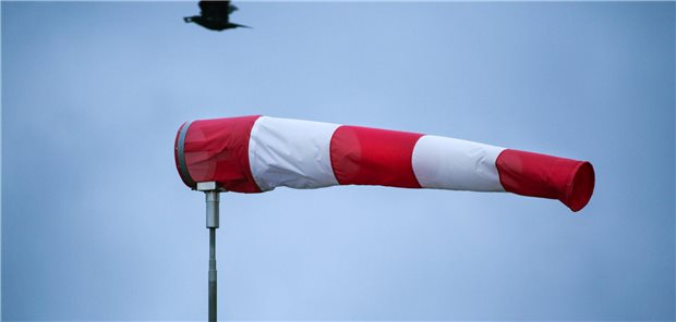 Geldanlage in stürmischen Zeiten: Durchhalten gehört dazu Windsack im Sturm, im Hintergrund fliegt eine Krähe