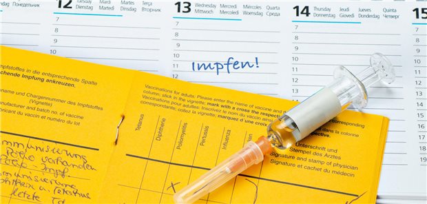 Hämatologische Neoplasien: Welche Impfungen bei Betroffenen sinnvoll sind Ein Impfpass und eine Spritze liegt auf einem Kalender mit Erinnerúng an einen Impftermin.