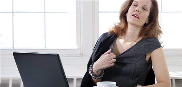 Wie die Menopause Körperprozesse beeinflusst Eine Frau in den Wechseljahren leidet unter Hitzewallungen.