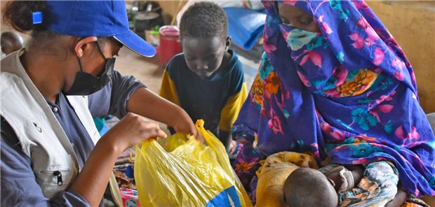 In einem Auffanglager in Al-Dschazira übergibt eine Helferin von Islamic Relief im Sudan ein Hilfspaket an eine Frau und ihre Kinder, die vor den Kämpfen geflohen sind.