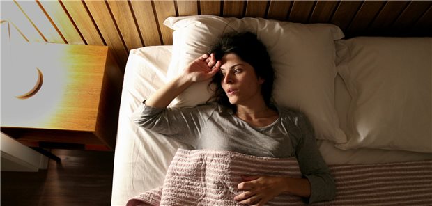 Schlafstörungen können Glaukom-Entstehung fördern Eine Frau mit Insomnie liegt in ihrem Bett und kann nicht einschlafen.