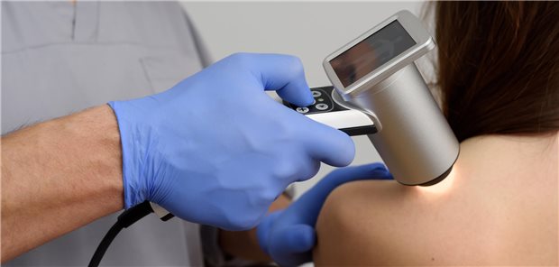 Künstlich intelligente Melanom-Diagnostik scheint verlässlich Nahaufnahme wie ein Dermatologe die Muttermale des Patienten mit einem Dermatoskop untersucht.