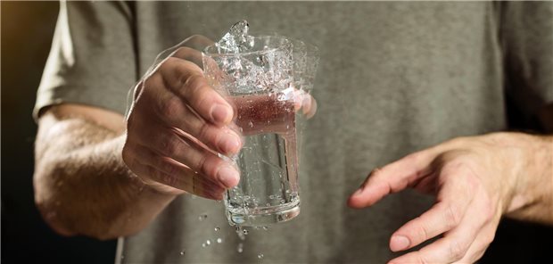 Wohl kaum Fortschritte in der Tremortherapie Ein Mann hält mit zitternder Hand ein Glas Wasser.
