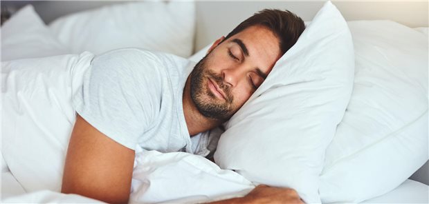 Sind zwei Kopfkissen für Menschen mit Glaukom eines zu viel? Ein Mann liegt schlafend auf zwei bequemen Kissen in einem Bett.