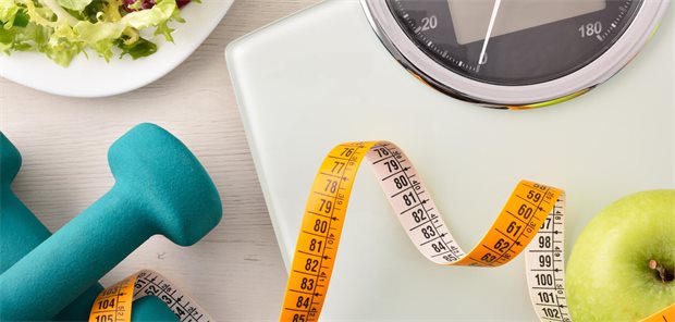 Jeder zweite junge Erwachsene erreicht Diabetesremission Auf einer Waage befindet sich ein Apfel sowie ein Maßband, daneben lieben Hanteln und ein grüner Blattsalat