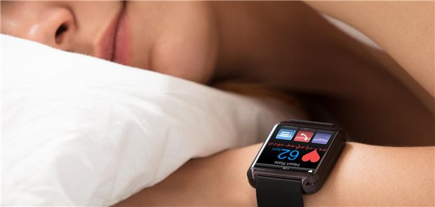 Frau schläft mit Smartwatch am Arm