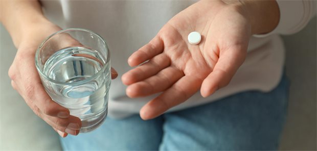 Einmal wöchentliche Kombitherapie erfolgreich bei HIV geprüft Person hält Glas Wasser in rechter Hand und weiße Tabeltte in linker Hand