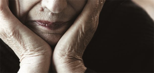 So spüren Sie eine Post-Stroke-Depression auf Eine ältere Frau stützt ihr Gesicht mit ihren Händen ab.