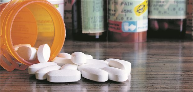 Langfristige Opioid-Therapie: An welchen Stellen sie verbessert werden kann Weiße Tabletten liegen vor einer orangenen Tablettendose. Im Hintergrund stehen weitere Dosen.
