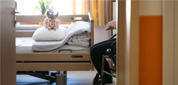 Pflegeversicherung: Berichte über hohe Defizite befeuern Reformdebatte Blick in ein Zimmer in einem Pflegeheim, dort steht ein Bett, daneben sitzt eine pflegebedürftiger Mensch.