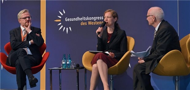 Wenn Reformen auf Realität treffen: Experten fordern mehr Mut und Ökonomie Amelie Wuppermann sitzt auf einem Podium zwischen zwei anderen Diskutanten und spricht ins Mikrofon.