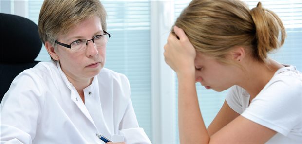 BMG lässt keine Einwände gegen Honorarverlust für Psychotherapeuten erkennen Frau im weißen Kittel schaut Mädchen an, das sich Hand vor die Stirn hält