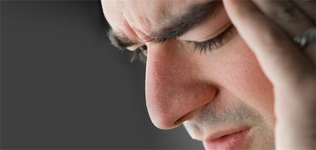 Nehmen Schmerzen mit dem Alter wirklich immer weiter zu? Ein Mann hält sich den Kopf und verzieht das Gesicht.