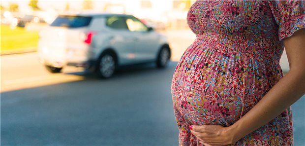 Schwangere Frau steht an einer Straße