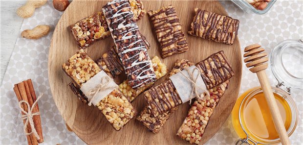 Reizdarmsyndrom: Ist die Glutensensitivität ein Nocebo-Phänomen? Ein Holzbrett mit verschieden Müsliriegeln auf einem Tisch.