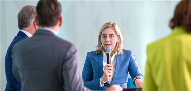 GKV-Sparpaket: Gesundheitsministerin Warken stellt sich Kritik der Pharmaindustrie auf offener Bühne Nina Warken steht auf der Bühne inmitten anderer Diskussionsteilnehmer, die man von hinten sieht.