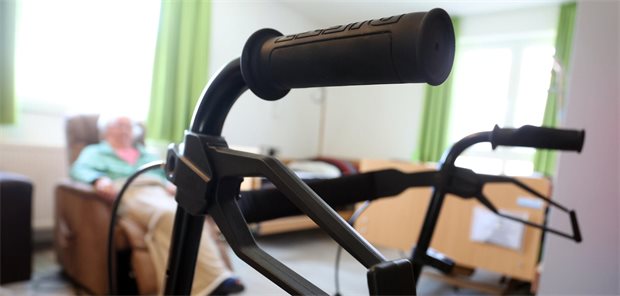 VDAB-Chef Knieling: Pflegevollversicherung gibt nur den schwarzen Peter weiter Eine pflegebedürftige Frau sitzt in einem Apartment hinter einem Rollator.