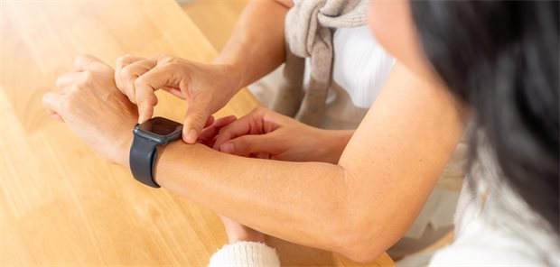 Hypertonie: Wenn die Smartwatch in falsche Sicherheit wiegt Die erwachsene Tochter zeigt ihrer älteren Mutter, wie man Healthtech-Geräte wie eine Smartwatch mit mobiler App nutzt, um zu Hause Gesundheit, Herzfrequenz und Blutdruck zu überwachen.