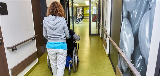 Pflegekraft schiebt Frau im Rollstuhl