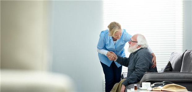 „Nicht nur am Rand“: Warum Pflege in der Primärversorgung ein Wort mitreden will Fachkraft im Heim unterstützt einen pflegebedürftigen Senior.