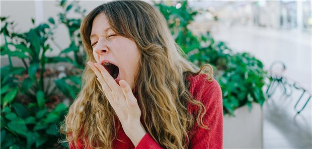 Schläfrige Patienten: Müdigkeitsanamnese auf keinen Fall verschlafen Eine müde Kundin gähnt und bedeckt ihren Mund mit der Hand, während sie in einem Einkaufszentrum wartet.