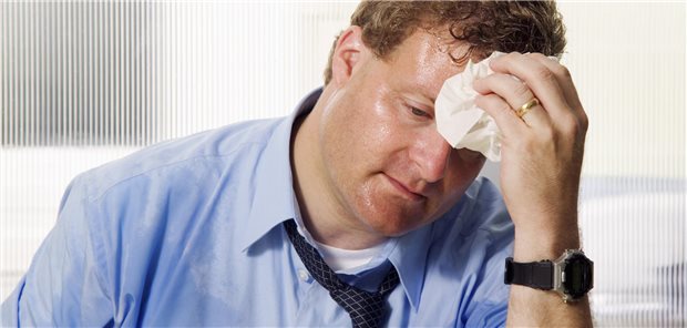 Das große Schwitzen: Strukturiert gegen Hyperhidrose vorgehen Ein Mann mit naßgeschwitztem Gesicht und Hemd tupft sich mit einem Tuch die Stirn ab.