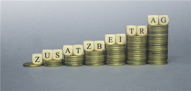 Reformdruck: GKV-Ausgaben steigen im ersten Quartal fast doppelt so stark wie die Einnahmen Würfel, die das Wort Zusatzbeitrag bilden, liegen auf Euromünzen.