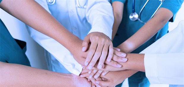 Studie: Immer mehr Hausarztpraxen setzen auf Teamarbeit Mehrere Hände unterschiedlicher Gesundheitsberufe übereinander gelegt.