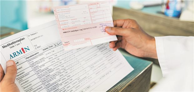 Ein Arzt hält einen Medikationsplan und ein Rezept auf Papier in der Hand