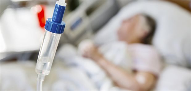 Vergütung sektorenübergreifender Versorgungseinrichtungen beschlossen Tropf im Vordergrund, liegender Patient (unscharf) im Hintergrund