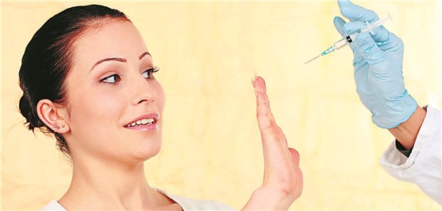 Gründe, warum sich Menschen für oder gegen eine Impfung entscheiden Eine Frau wehrt mit ihrer Hand eine sich ihr nähernde Hand, die eine Impfspritze hält, ab.