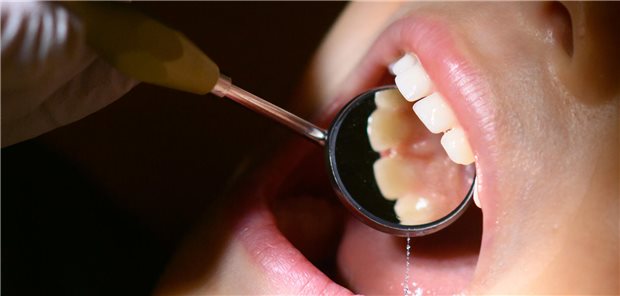 Zahnarzt untersucht Mund einer Patientin.